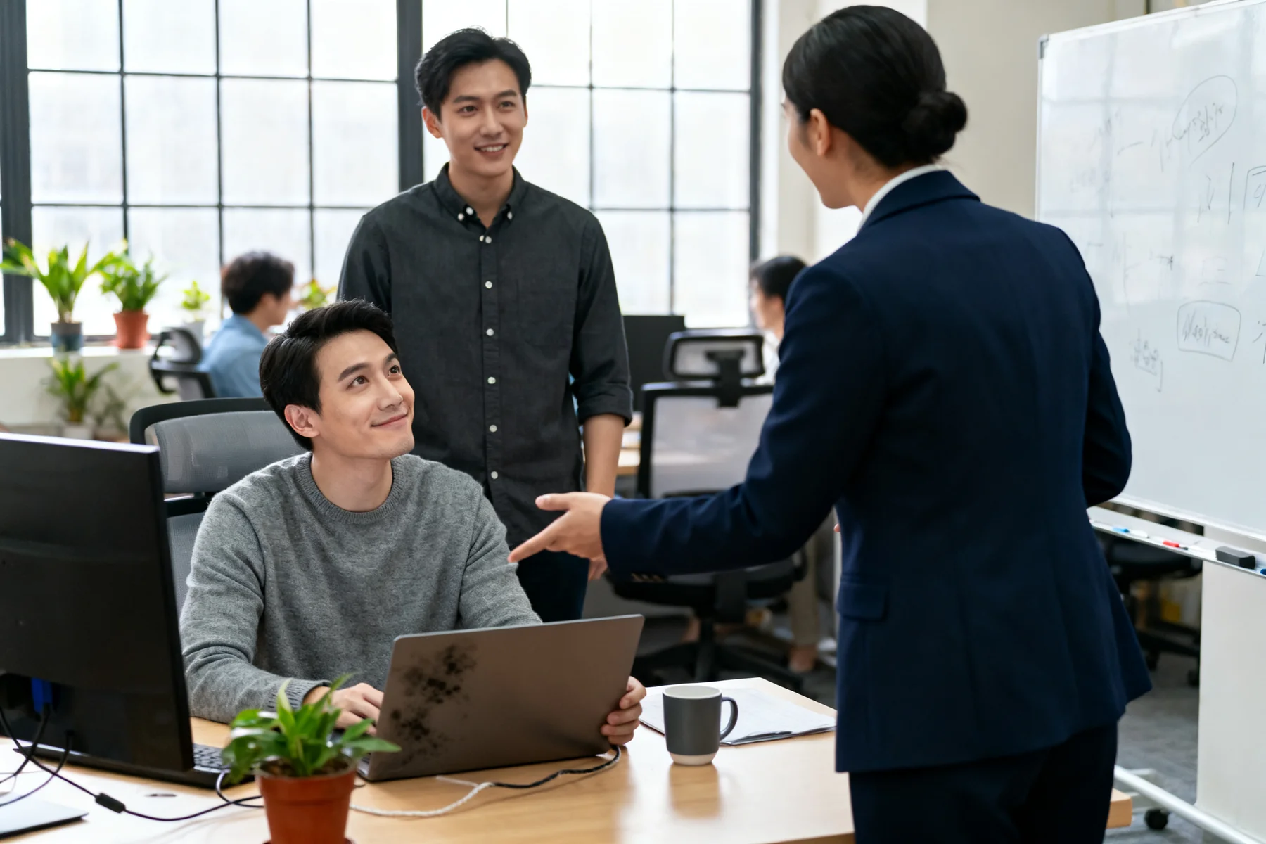 Team lead introducing a new employee to a colleague at a workstation.
